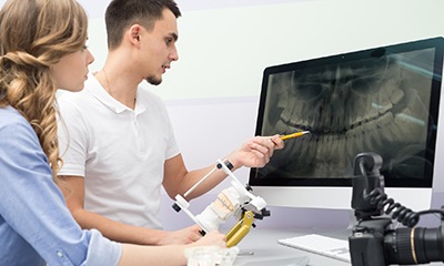 Dental assistant and patient looking at dental x-rays