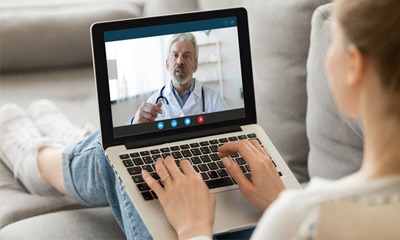 A dentist speaking with a patient over a video call.