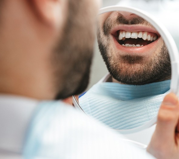 Patient smiling at reflection in handheld mirror