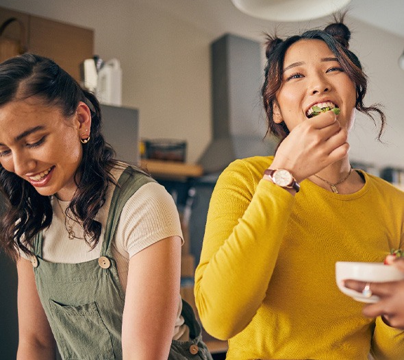 Friends smiling while eating together in kitchen