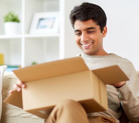 Man smiling while opening package on couch