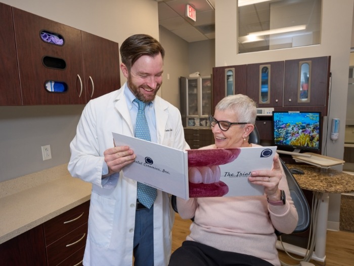 Dentist showing patient book featuring smiles