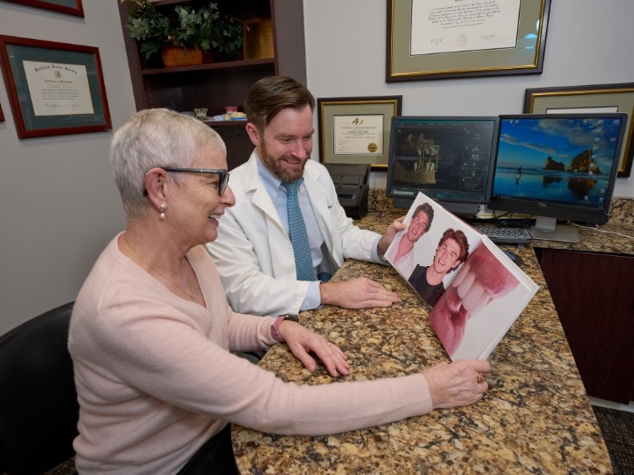 Dentist showing patient book that illustrates results of treatment