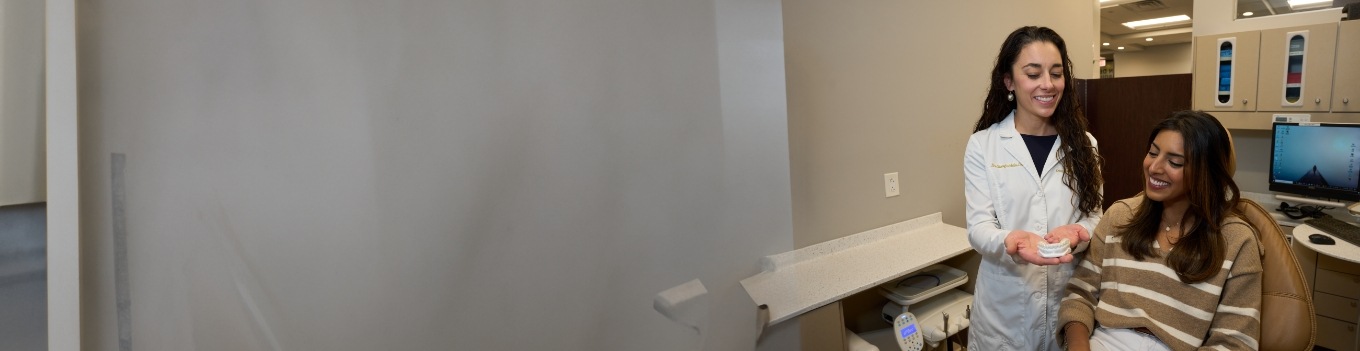 Female dentist showing patient model of teeth