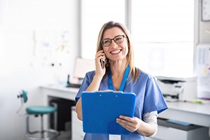 dental team member holding a clipboard while talking on the phone 