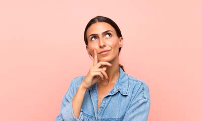 Woman with hand on her chin thinking with pink background