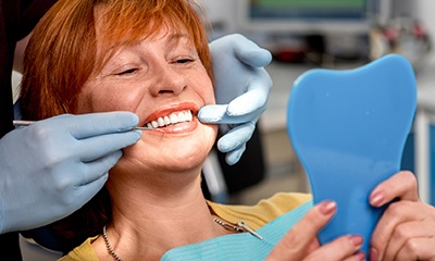 Woman looking at teeth and gums in mirror