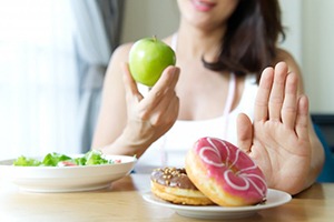 woman choosing to eat an apple instead of donuts 