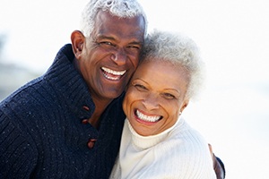 An older couple laughing and smiling together and enjoying their new and improved smiles thanks to financing their dental implants