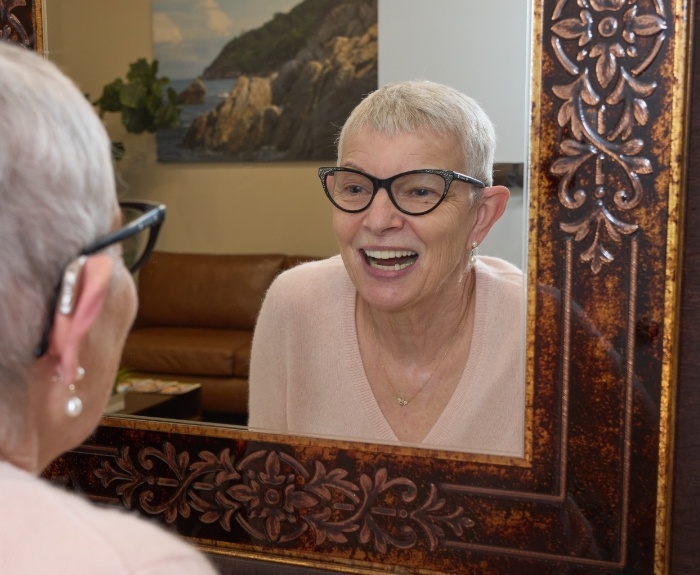 Senior dental patient in front of a mirror looking at her smile