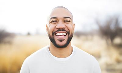Man in white shirt smiling outside
