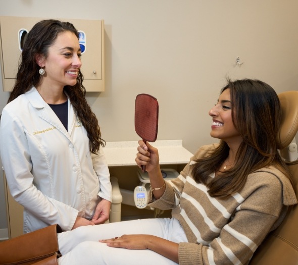 Female patient holding a mirror and smiling
