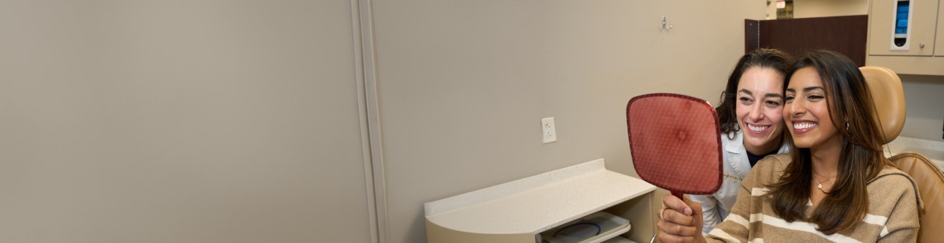 Patient and dentist looking into handheld mirror together