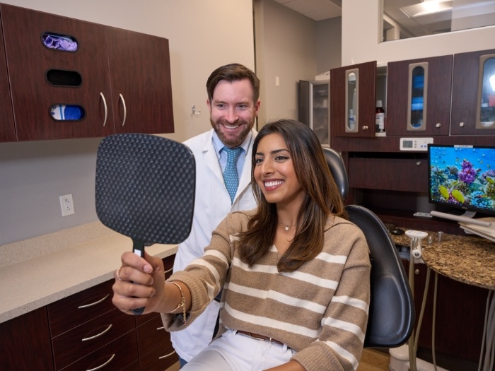 Male dentist and female patient smiling