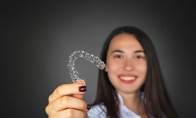 Woman holding Invisalign clear aligner.