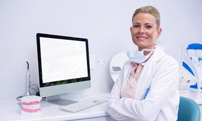 Dentist folding her arms in front of a computer.