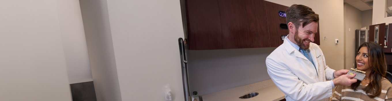 Male dentist shade-matching patient's smile