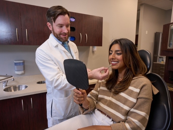 Female patient holding up mirror and smiling
