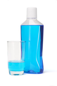 blue mouthwash in bottle and glass