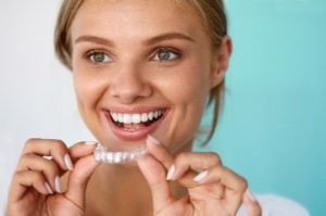 Smiling woman putting a whitening tray in