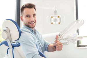 smiling man giving thumbs up in dental treatment chair