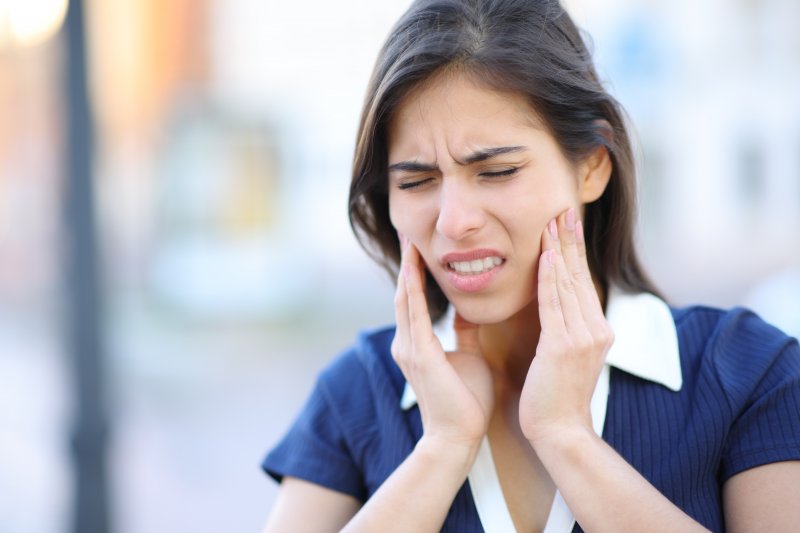 Woman holds face with pained expression.